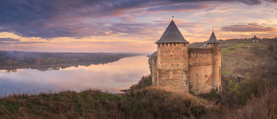 panoramic view to old medieval fortress in Ukraine on the bank of river Dniester after sunset