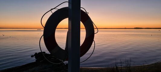 Beautiful view of a lifebuoy on a shore during orange sunset with clear sky