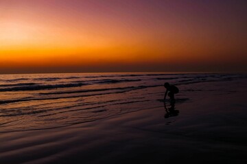 Silhouette of kid playing on beach during sunset