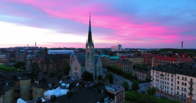Aerial Backward Shot Of Lutheran Church Amidst Buildings In City During Sunset Against Sky - Stockholm, Sweden