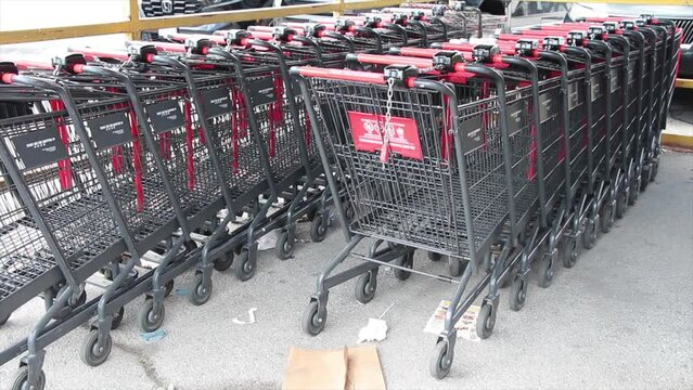 grocery shopping carts buggies parked inside each other inside under corral canopy rain cover outside outdoors exterior, red silver