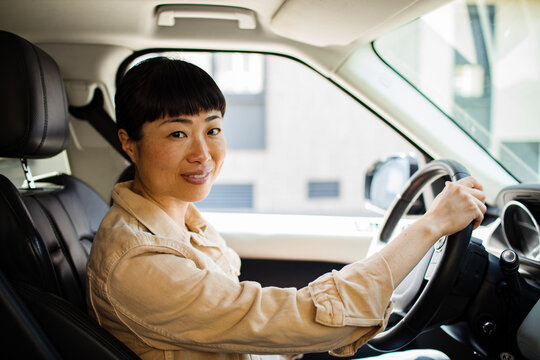 Asian woman driving car looking at camera