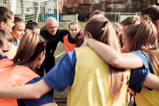 Coach Strategizing with Youth Soccer Players on the Field