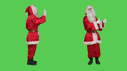Santa does no sign and gives thumbs up on both sides on the full body greenscreen studio, wearing festive red suit and hat. Father christmas expressing frustration, doing like agreement symbol.