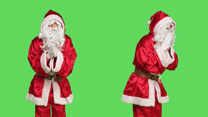 Saint nick character praying on camera, holding hands in a prayer and posing on greenscreen during...