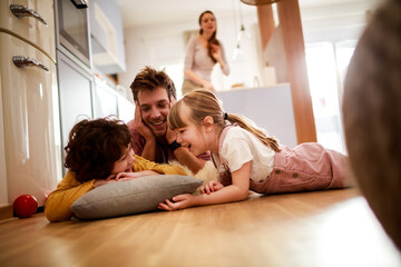 Happy young dad having fun with his kids on the floor at home