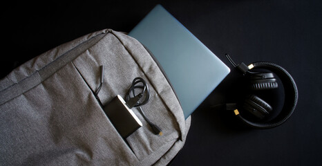 Gray textile city backpack with a blue laptop or ultrabook, an external battery - power bank and...