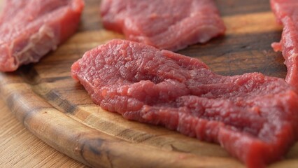 Close-up dolly shot of Sliced Raw Beef on Wooden Board.