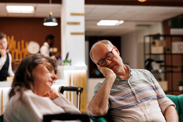 During their vacation, worn-out retired senior customers relax on a comfortable couch in the lounge...
