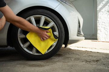 A Man Cleaning the Wheels of a Car with a Yellow Cloth. Car Detailing and Cleaning Concept with Space for Copy