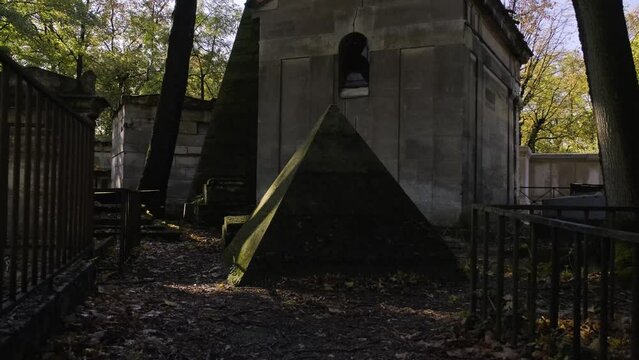 Moving forward view of advancing towards a strange small pyramid in Pere Lachaise cemetery