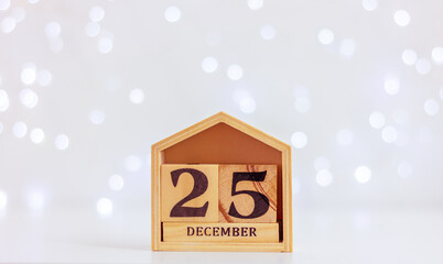 wooden calendar with date 25 December on background of festive lights. celebration, winter...