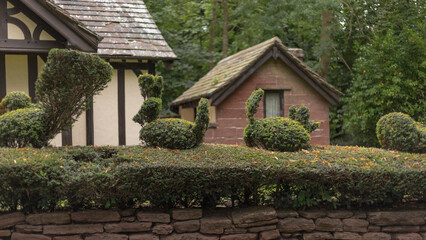 Topiary animals on the top of a yew hedge with buildings in the background
