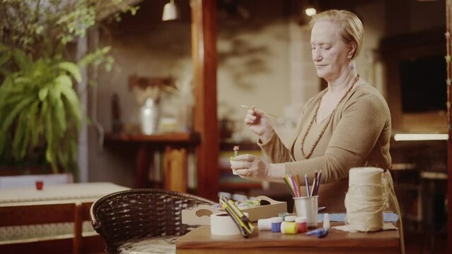 Mulher idosa sorridente apreciando o trabalho de ceramica em casa. Cinematico 4k.