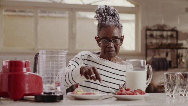 Mulher senior feliz fazendo vitamina saudavel de pela manha na cozinha de casa. Cinematico 4k.