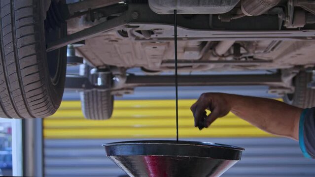 Draining Oil from Old Car Engine from Crankcase in Repair Shop Footage.