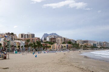 Fototapeta na wymiar Sea waves splashing over the shore with the city in the background, Alicante, Spain