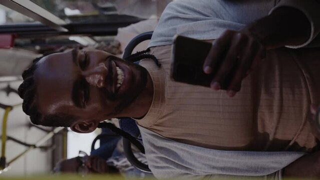 Jovem negro usando smartphone durante uma viagem de onibus. Cinematico 4k. Video vertical.