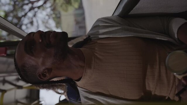 Homem negro, sorrindo, olhando pela janela do onibus. Cinematico 4k. Video vertical.