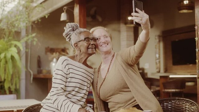 Duas mulheres idosas tirando selfie com smartphone, durante o cafe da tarde. Cinematico 4k.