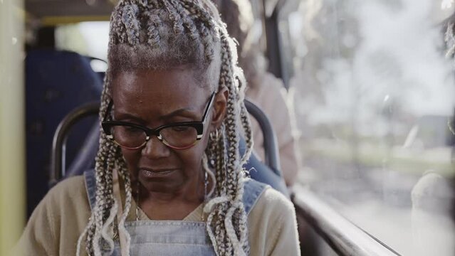 Mulher negra senior com penteado afro sentada no onibus. Cinematico 4k.