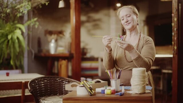 Artista senior feliz pintando um vaso de ceramica. Cinematico 4k.