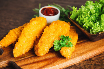 Semifinished Breaded chicken nuggets from chicken fillet on a dark background with fresh herbs.Fast food. Quick cooking at home. Breaded Chicken Inner Fillet. Fast cooking.Chicken nuggets with salad.
