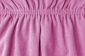 Pink corduroy fabric gathered with elastic close-up. Velveteen texture with folds and drapery....