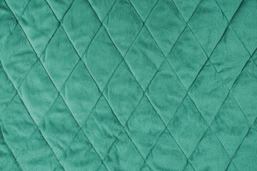 Quilted velours fabric background. Green texture blanket or puffer jacket, stiched with diamond...