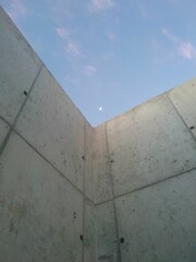 Vertical shot of a wall with the moon visible in the sky during the afternoon