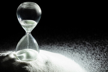 Hourglass add more sand of time on white sand over black background. White hourglass show more time...