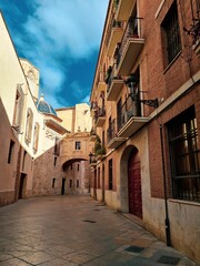 Fototapeta na wymiar Vertical shot of an alley between old buildings under a blue sky