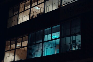 Low angle shot of the large windows of apartment buildings with colorful lights during nighttime