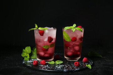 Board with glasses of fresh raspberry mojito on black background
