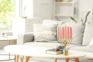 Menorah with Torah and dreidels for Hanukkah on table in living room