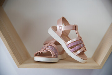 Pair of pink sandals for a girl on a wooden shelf