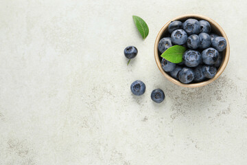 Tasty fresh blueberries in bowl on light table, flat lay. Space for text