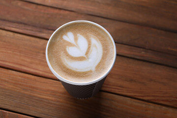 Coffee to go. Paper cup with tasty drink on wooden table, above view