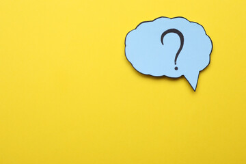 Paper speech bubble with question mark on yellow background, top view. Space for text