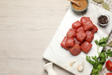 Raw beef meat and different ingredients for cooking delicious goulash on light wooden table, flat...