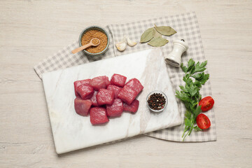 Raw beef meat and different ingredients for cooking delicious goulash on light wooden table, flat...