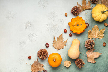 Fresh pumpkins with chestnuts, cones and autumn leaves on grunge background