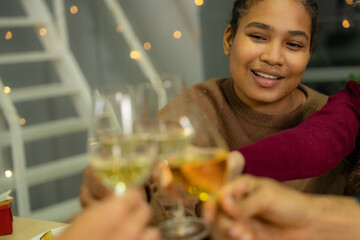 close up glasses of clinking glasses of champagne with lighting. Dinner party with drinking of champagne. hands holding clear glass with alcohol in yellow shine reflect.
