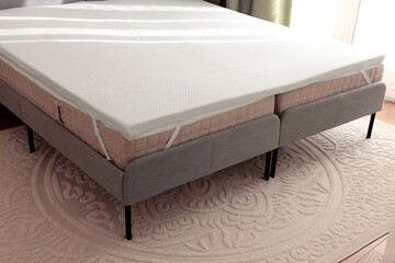White memory foam mattress topper on grey bed indoors