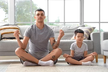 Foto op Canvas Young man with his little son meditating at home © Pixel-Shot