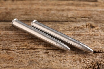 Two metal bullets on wooden table, closeup