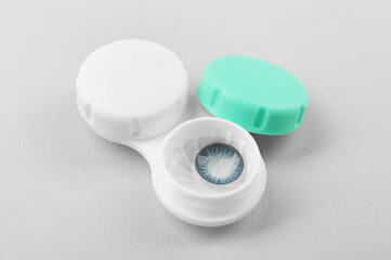 Case with blue contact lenses on light grey background