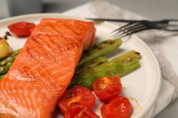 Tasty grilled salmon with asparagus and tomatoes on table, closeup