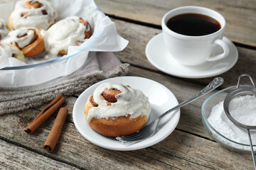 Tasty cinnamon rolls with cream served on wooden table