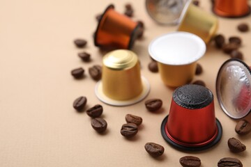 Obraz na płótnie Canvas Many coffee capsules and beans on beige background, closeup. Space for text
